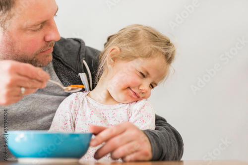 Father feeding his daughter, she turning away photo