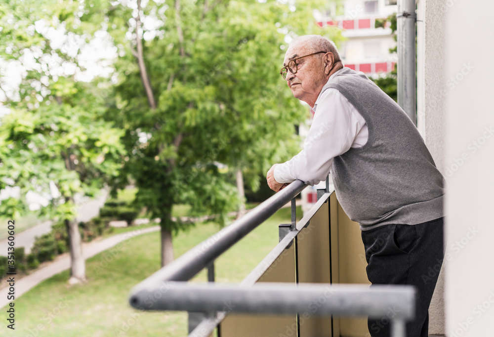 Senior man standing on balcony looking at distance Senior man standing on balcony looking at distance