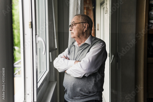 Pensive senior man looking out of window