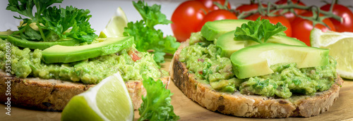 Slice of bread with guacamole made from avocado  tomato  lime  poarsley and garlic - close up  - banner design