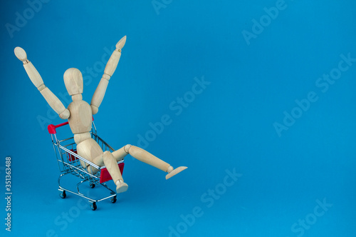 wooden mannequin in a shopping cart, shopping concept at sales