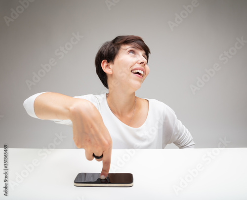 Smug woman pointing to her mobile phone