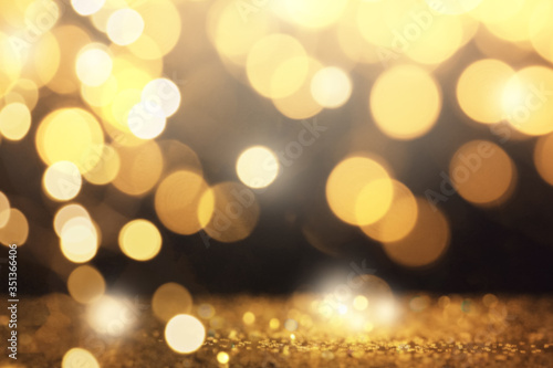 Blurred view of gold glitter on dark background  bokeh effect