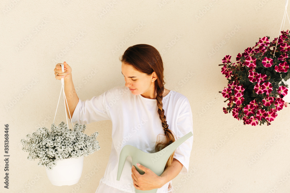 Lovely housewife with flower in pot and watering can Lovely housewife with flower in pot and watering can