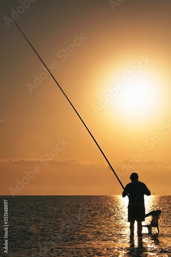 Fisherman catches fish at sunrise in mediterranean sea