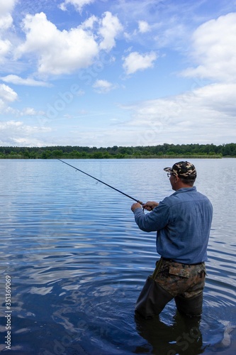 Angler catching the fish in the lake durring summer day