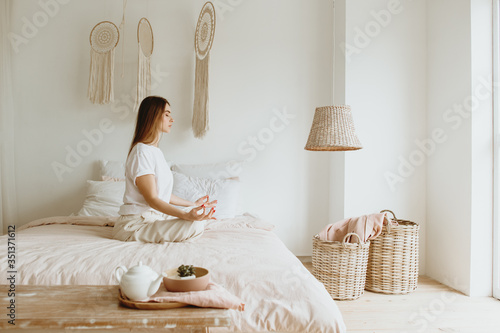 Young woman practicing meditation on bed.
