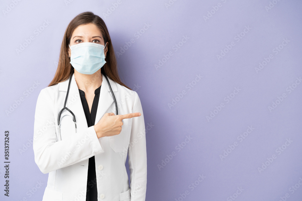 Physician with mask pointing at copy space Physician with mask pointing at copy space