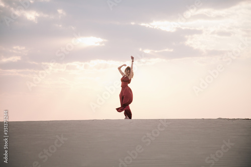 Girl in red dress at sunset in the desert