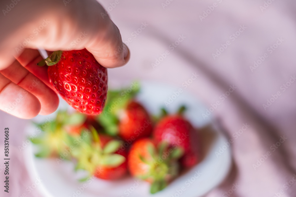 Obraz premium Portrait of a man's hand with a strawberry. Concept: breakfast,