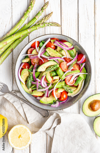 Healthy vegan meal, Juicy summer salad with blanched asparagus, cherry tomatoes, avocado slices and red onion, sprinkled with pepper and drizzled with olive oil and lemon juice