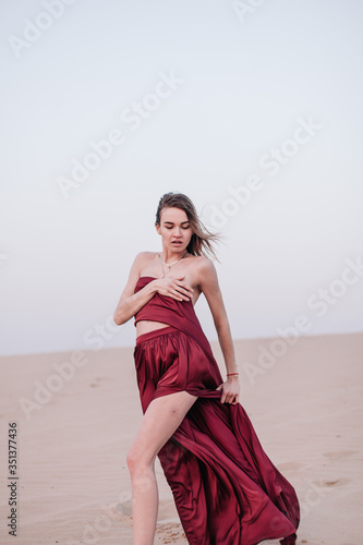 Girl with red cloth in the sunset rays in the desert