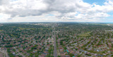 Artistic view of Toronto city at cloudy sky day. Panoramic summer landscape in  Ontario, Canada. North American urban commuter background of houses, stores, parking, and roads with green trees.