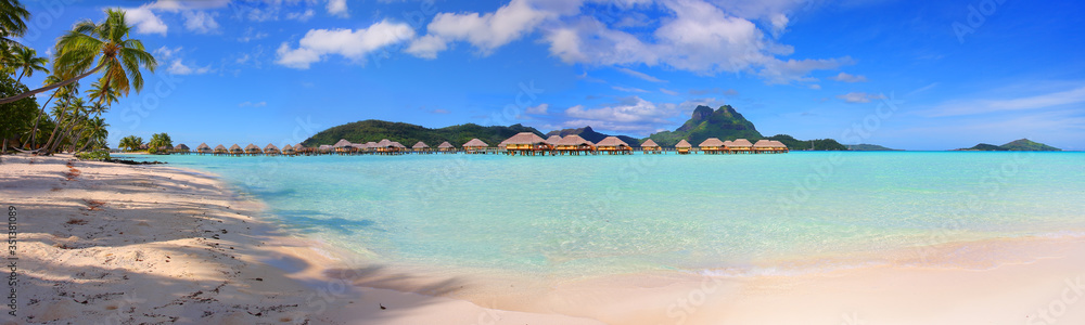 Panoramic view of turquoise Bora Bora lagoon with overwater huts and mountains