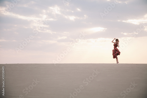 Girl in red dress at sunset in the desert