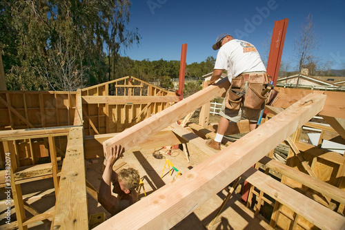 Workers position support beams into framing of house in Southern California