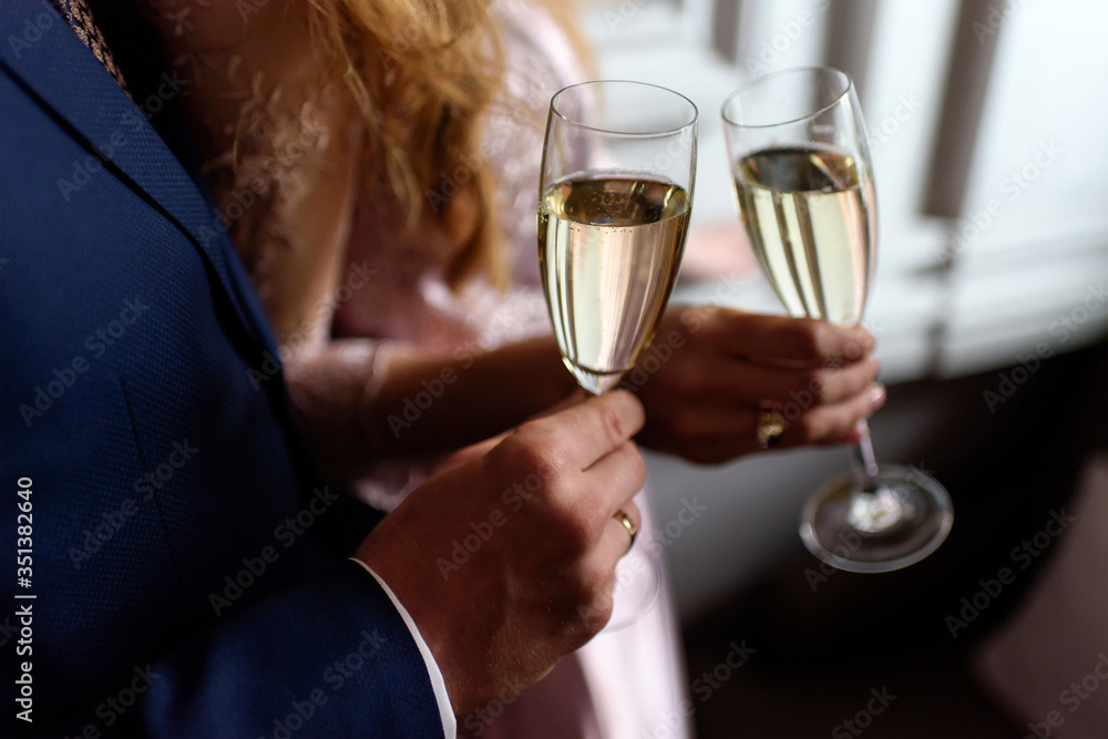 Man and a woman hands holding two glasses of champagne or wine. Couple in a romantic engagement or anniversary celebration. Close-up, selective focus. Man and a woman hands holding two glasses of champagne or wine. Couple in a romantic engagement or anniversary celebration. Close-up, selective focus.