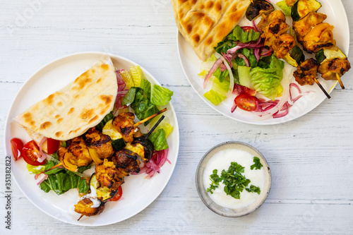 Chicken and courgette spicy tandori skewers with salad and flat bread photo