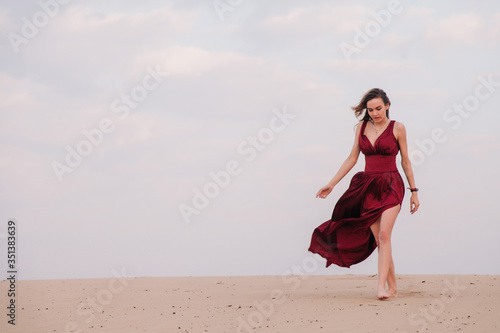 Girl in red dress at sunset in the desert