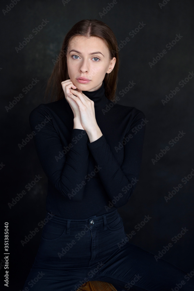 Portrait of beautiful brunette, touching subtle her face. Natural beauty. Wear black clothes, turtleneck blouse with long sleeves. Dark background. Portrait of beautiful brunette, touching subtle her face. Natural beauty. Wear black clothes, turtleneck blouse with long sleeves. Dark background.