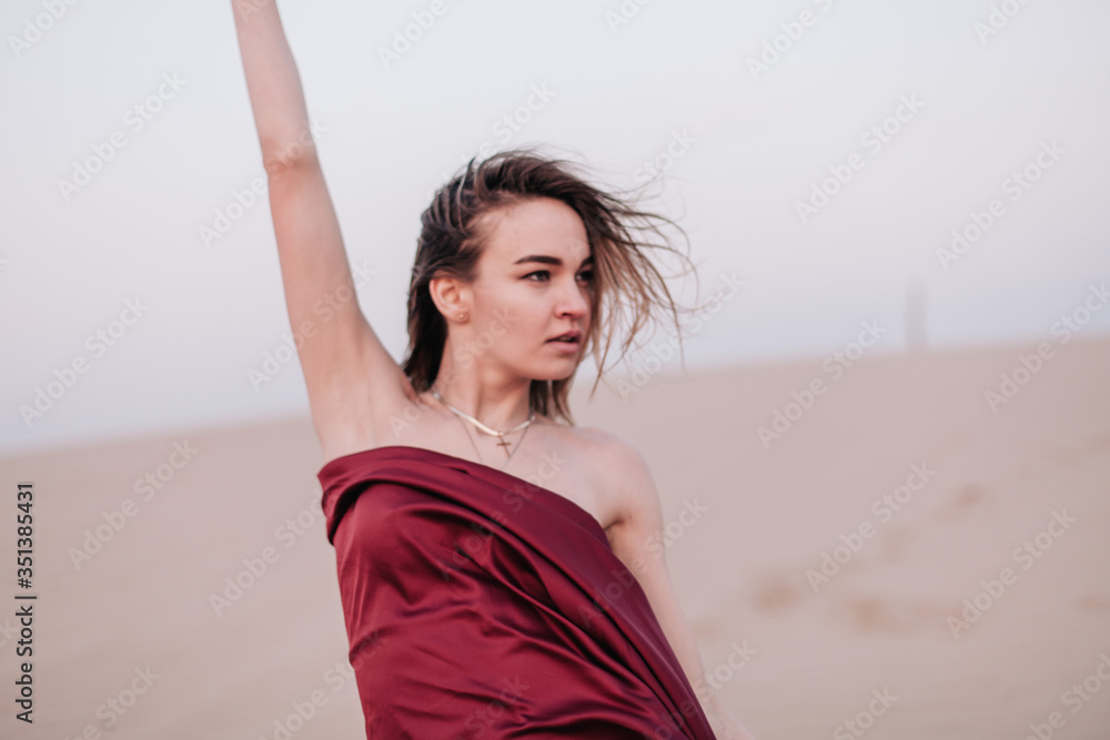 Girl with red cloth in the sunset rays in the desert Girl with red cloth in the sunset rays in the desert