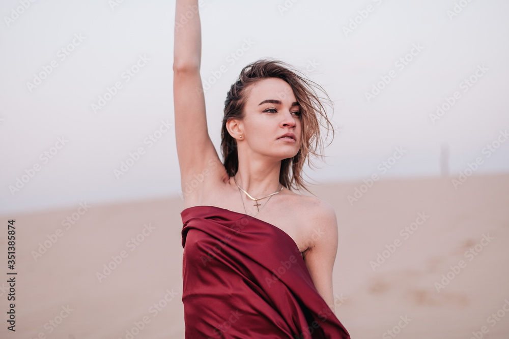 Girl with red cloth in the sunset rays in the desert Girl with red cloth in the sunset rays in the desert