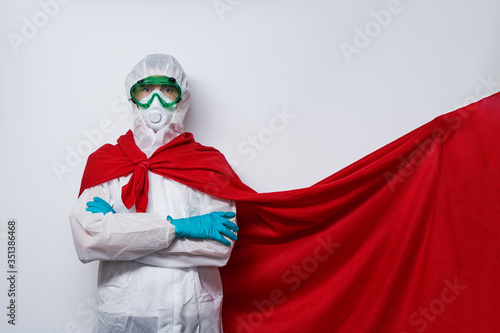 Doctor is wearing PPE - costume, gloves and surgical face mask in superhero cape.