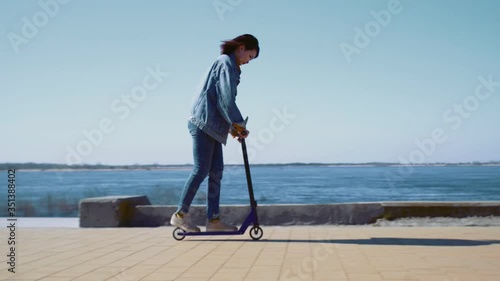 Young asian woman in a jeans jacket rides the scooter near the river photo