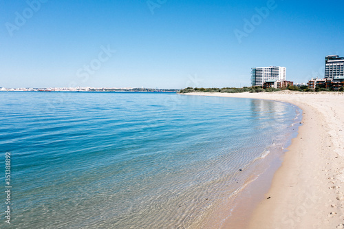 Landscape View of the perfect white sandy beach with breaking waves. Transparent sea water. Paradise and desert beach in Troia, Setubal, Portugal. Arrabida mountain in the background