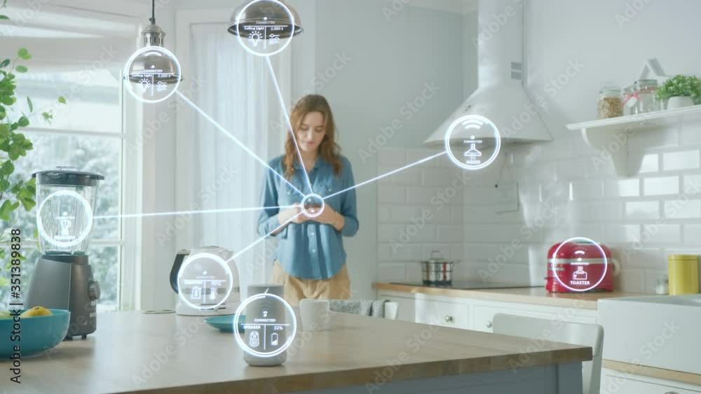 Internet of Things Concept: Young Woman Using Smartphone in Kitchen. She controls her Kitchen Appliances with IOT. Graphics Showing Digitalization Visualization of Connected Home Electronics Devices