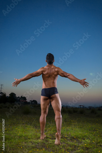 young Mexican bodybuilder back muscles posing outdoors 