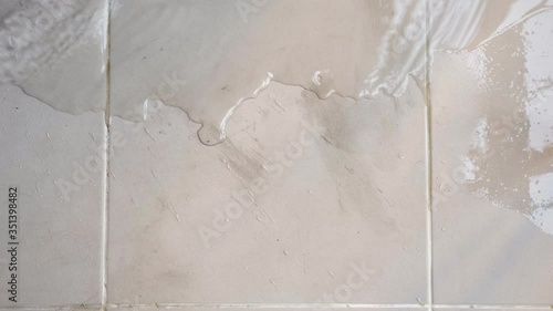 transparent water spreads across floor white tile top view