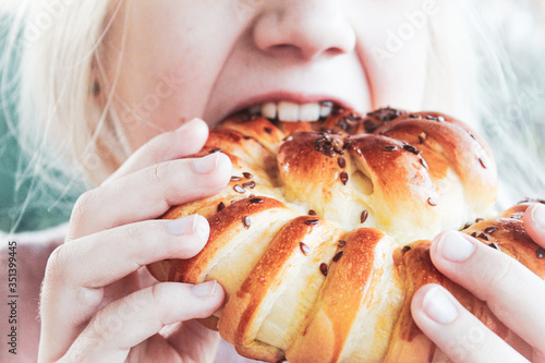 Girl eats a fresh and lush bun close-up  selective focus.