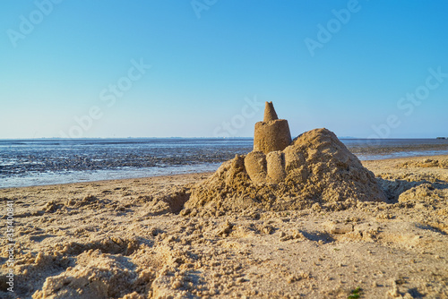 Sandcastle on the beach in Dangast, district Friesland, Germany against blue sky on a sunny spring day