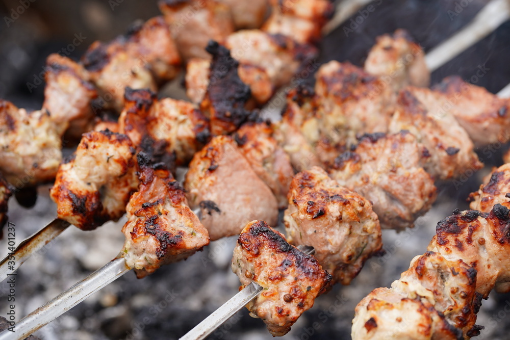 Close up of toasted shashlik on skewers. Succulent barbecue roasting on chargrill. Concept of picnic outdoor.