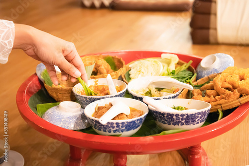 People picking fresh vegetables dipped in chili paste in Khantoke. There are many food bowls in Northern Thailand.