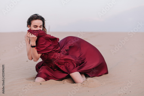 Girl with red cloth sits on the sand