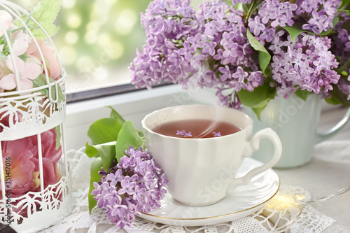 cup of tea and bunch of lilac blossom on window sill