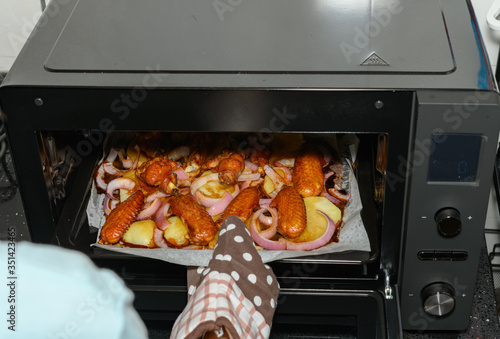 taking out fresh baked chicken wing with onion and potato from oven