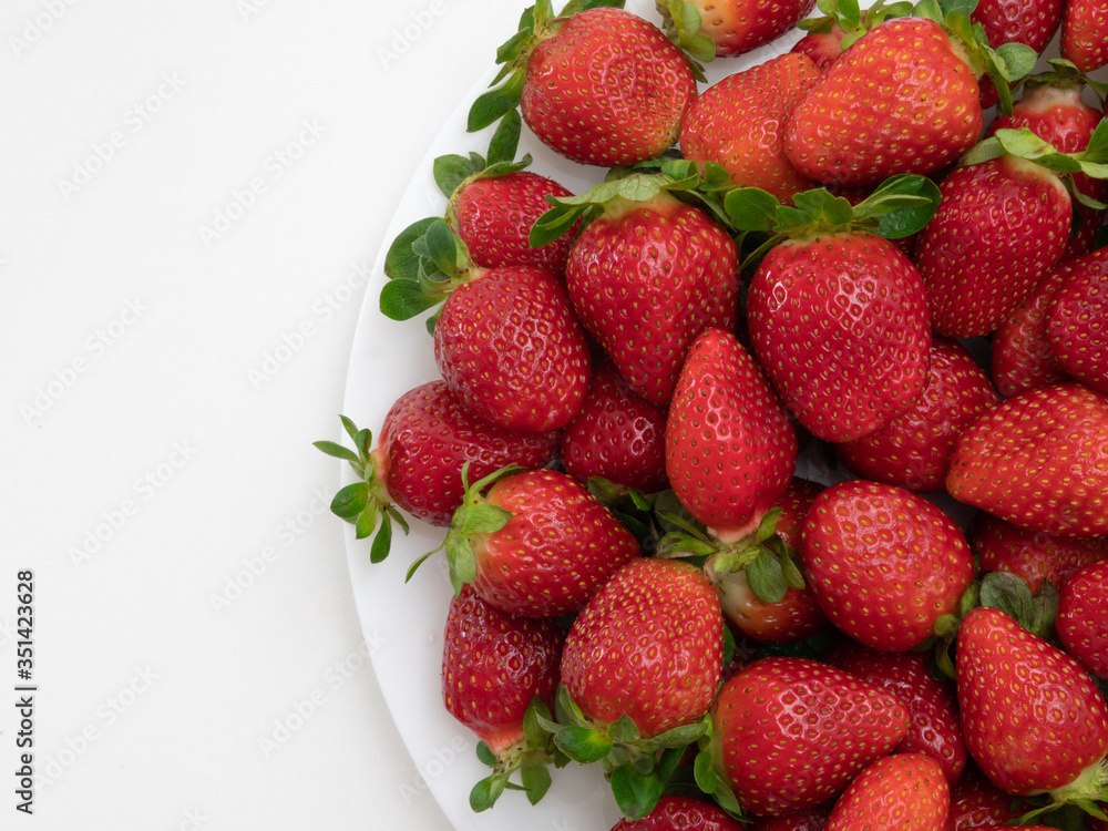Top view. Copy space. Many strawberries in the white dish and white background. Top view. Copy space. Many strawberries in the white dish and white background.
