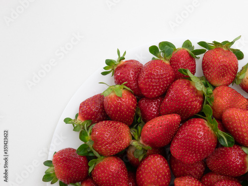 Top view. Copy space. Many strawberries in the white dish and white background.