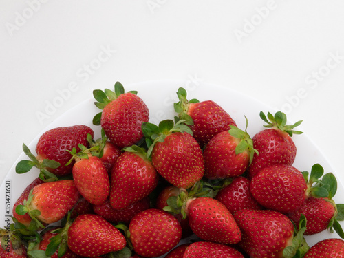 Top view. Copy space. Many strawberries in the white dish and white background.