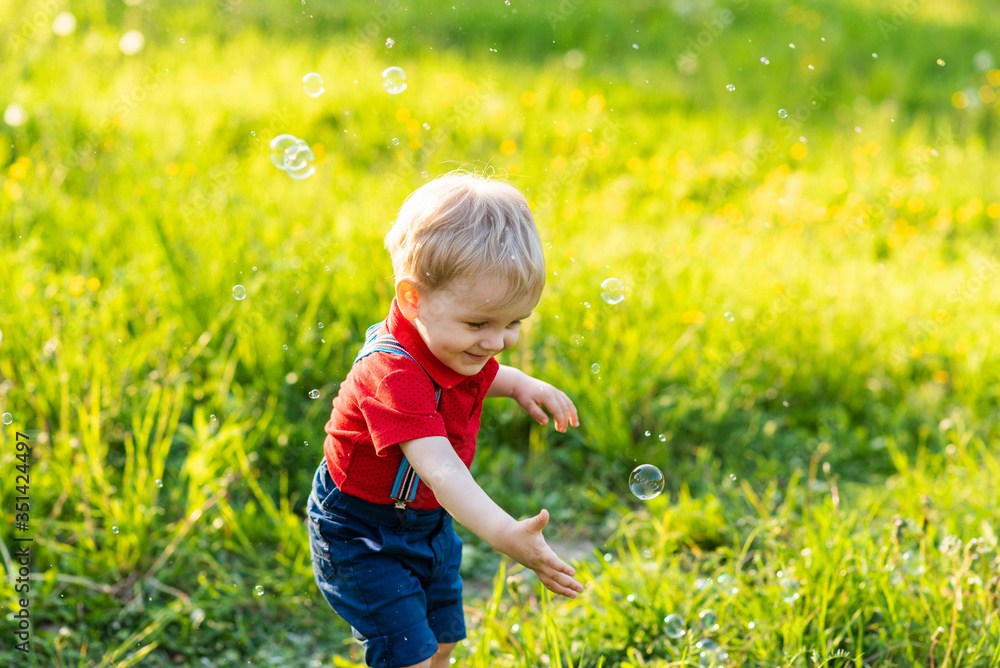 child boy has fun playing in nature with shiny soap bubbles child boy has fun playing in nature with shiny soap bubbles
