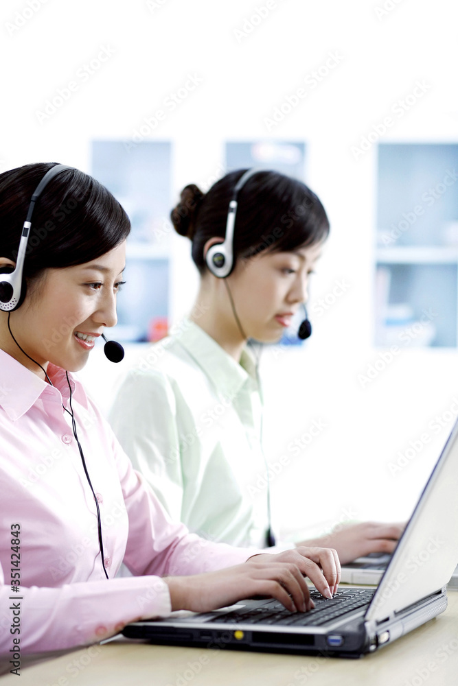 Businesswomen using laptop and microphone headsets Businesswomen using laptop and microphone headsets
