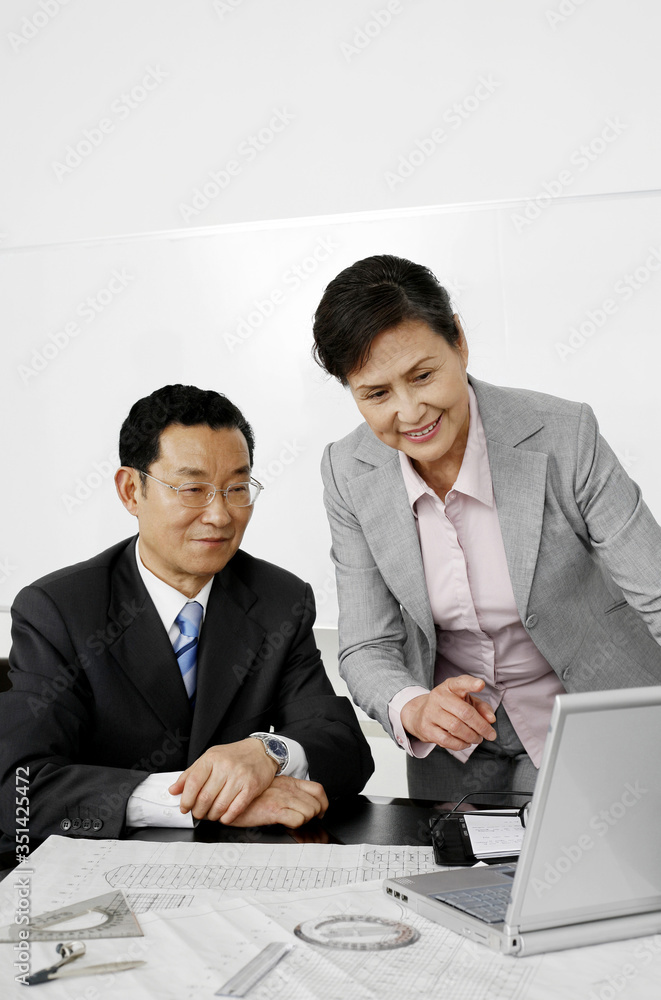 Business people using laptop while having discussion Business people using laptop while having discussion