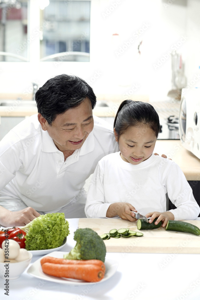 Senior man and girl preparing food in the kitchen Senior man and girl preparing food in the kitchen