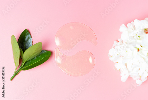 Tela Moisturizing collagen patches and green leaves on pink background, concept of fa