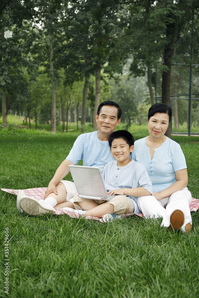 Senior man, senior woman and boy smiling at the camera while using laptop Senior man, senior woman and boy smiling at the camera while using laptop