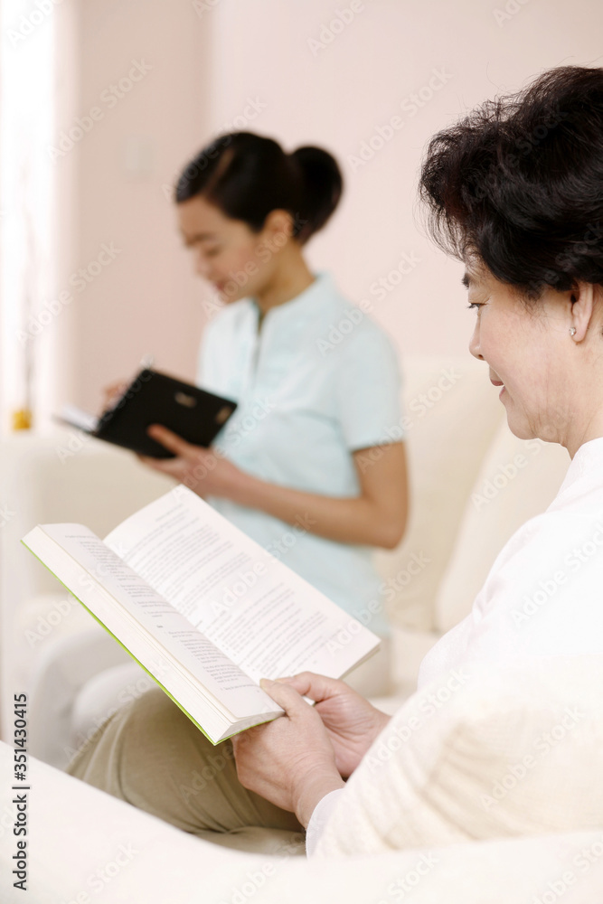 Woman reading book, another woman writing diary in the background Woman reading book, another woman writing diary in the background