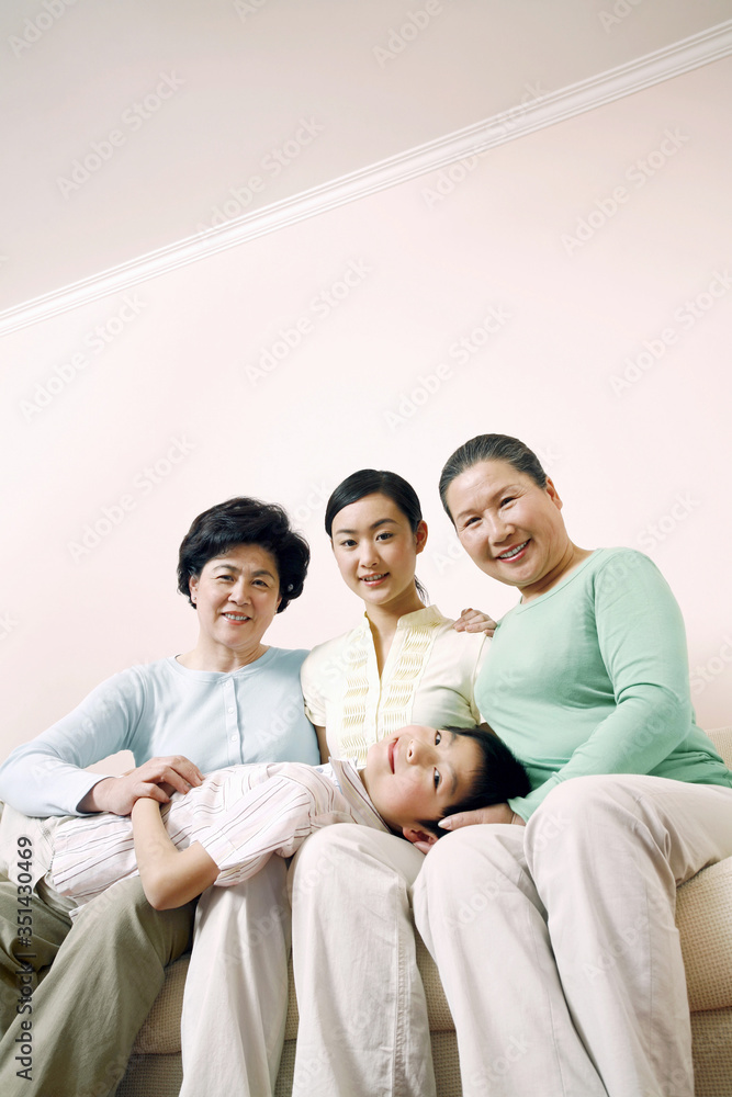 Female generations of a family sitting on couch, boy lying on their laps Female generations of a family sitting on couch, boy lying on their laps